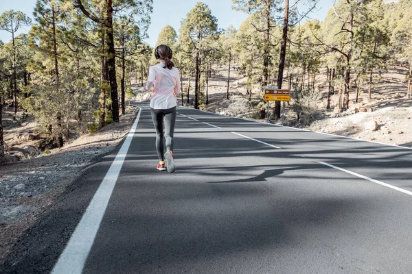 Женщина бегает по горной дороге — стоковое фото