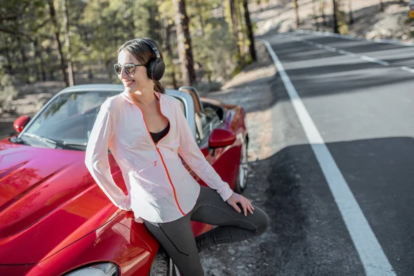 Sports woman near the car on the mountain road — Stockfoto