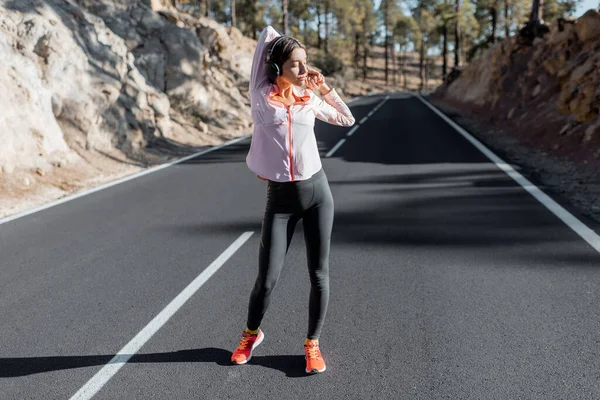 Woman exercising on the mountain road — Stockfoto