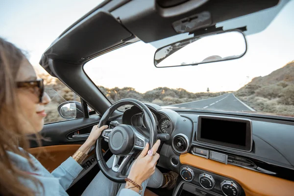 Woman traveling by cabriolet on the desert road — Stockfoto