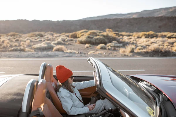 Woman traveling by cabriolet on the desert road — 图库照片