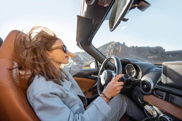 Woman traveling by cabriolet on the desert road — Stock fotografie