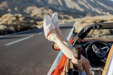 Woman pulling legs out of the car window on the roadside