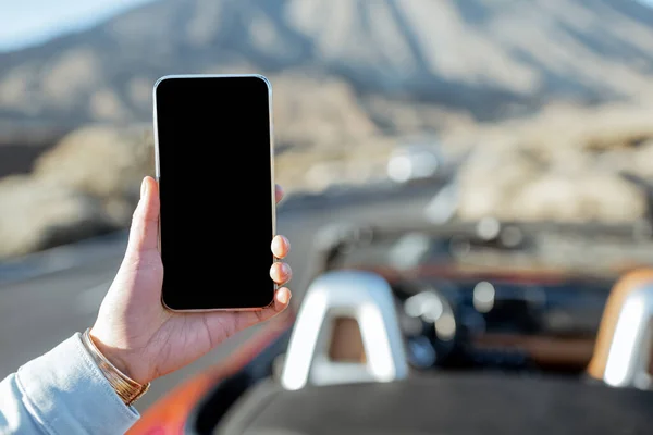 Holding phone with empty screen on the roadside — 图库照片