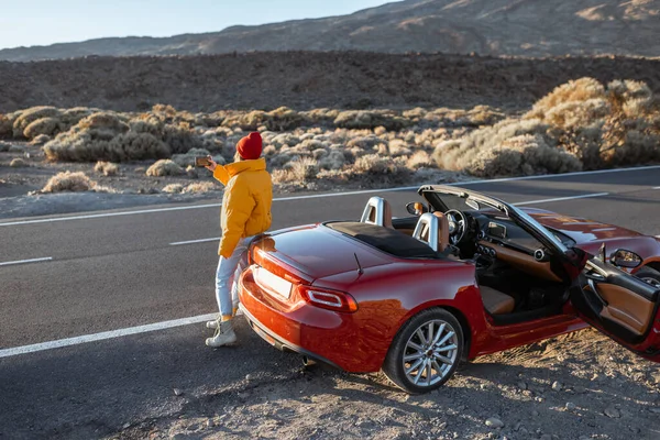 Woman traveling by car on a desert valley — Stockfoto