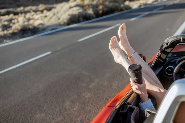 Woman pulling legs out of the car window on the roadside — Zdjęcie stockowe