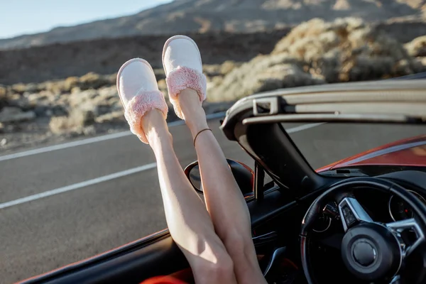 Woman pulling legs out of the car window on the roadside — Stok fotoğraf