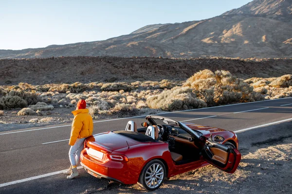 Woman traveling by car on a desert valley — Stockfoto