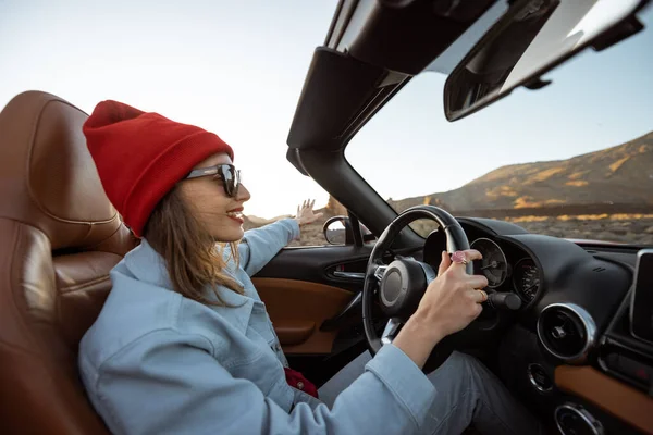 Woman traveling by cabriolet on the desert road — Stockfoto