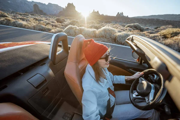 Woman traveling by cabriolet on the desert road — Stockfoto