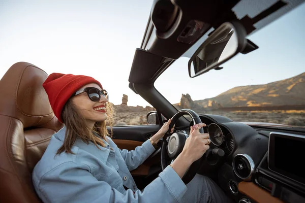 Woman traveling by cabriolet on the desert road — Stockfoto