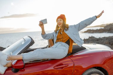 Woman vlogging on phone while travel on the ocean coast
