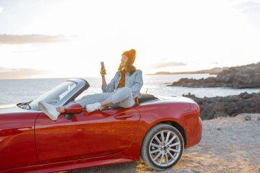 Woman vlogging on phone while travel on the ocean coast