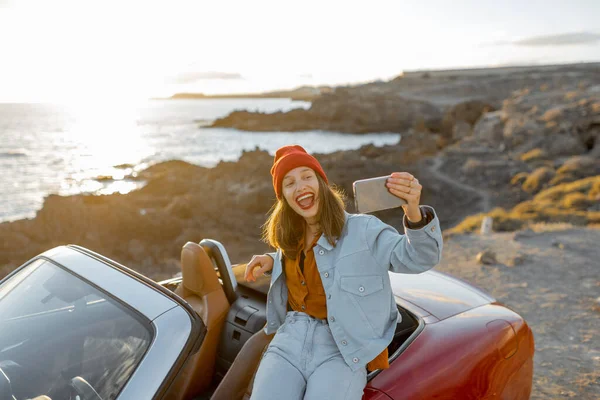 Mujer vlogging en el teléfono mientras viaja en la costa del océano — Foto de Stock