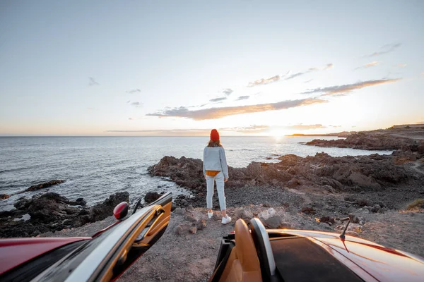 Женщина, путешествующая на машине по скалистому океану — стоковое фото
