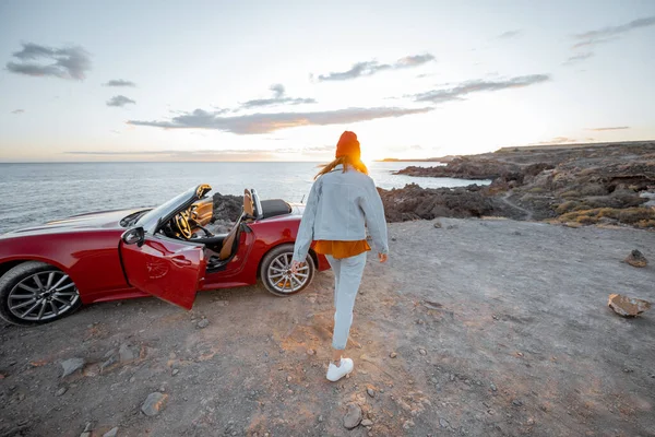 Woman traveling by car on the rocky ocean coast — Stockfoto