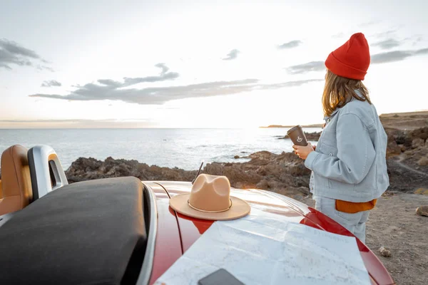 Woman traveling by car on the rocky ocean coast — Stockfoto