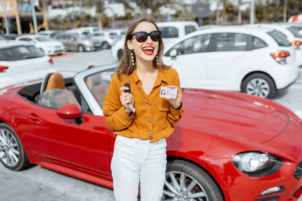 Mulher com chaves e licença perto do carro no estacionamento — Fotografia de Stock