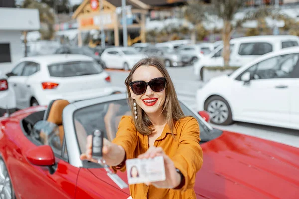 Mujer con llaves y licencia cerca del coche en el aparcamiento — Foto de Stock