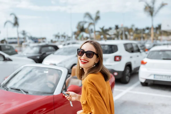 Mujer feliz con llaves cerca del coche en el aparcamiento —  Fotos de Stock