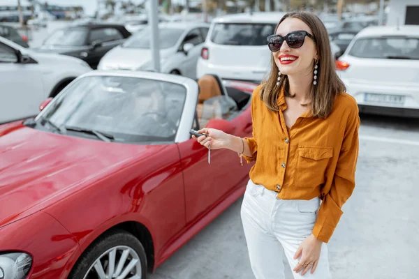 Mulher feliz com chaves perto do carro no estacionamento — Fotografia de Stock