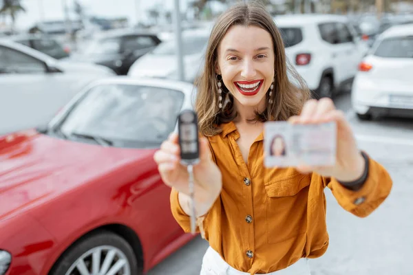 Mujer con llaves y licencia cerca del coche en el aparcamiento — Foto de Stock