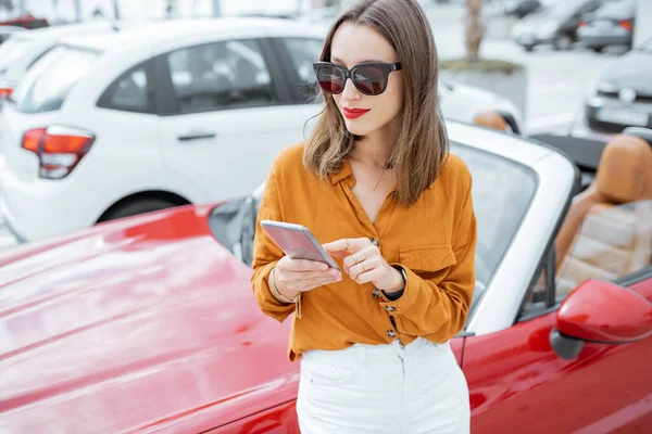 Woman with phone at the car parking — Stockfoto