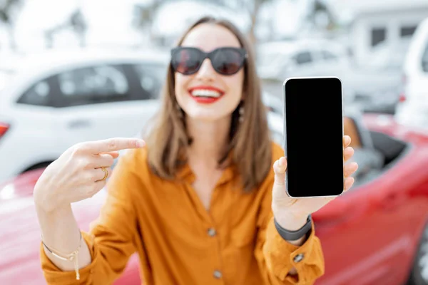 Woman with smart phone at the car parking — Φωτογραφία Αρχείου