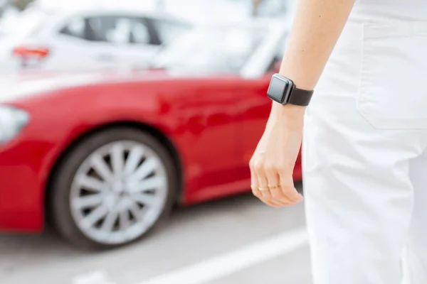 Smart watch on womens wrist with car on the background, close-up — Zdjęcie stockowe