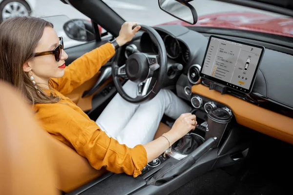 Mujer conduciendo coche deportivo con una pantalla táctil digital — Foto de Stock