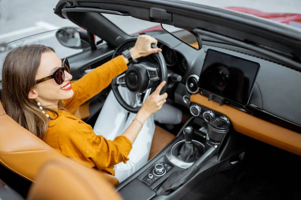 Mulher dirigindo carro esporte com uma tela sensível ao toque digital — Fotografia de Stock
