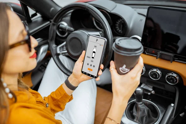 Mujer que controla el coche con un teléfono inteligente — Foto de Stock