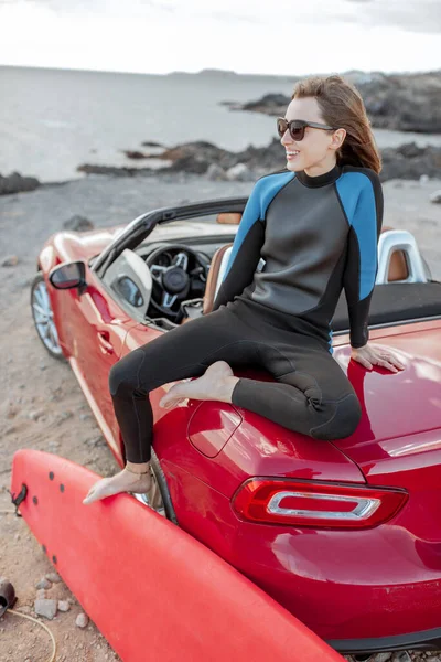 Young surfer with surfboard on the sports car on the beach — Stockfoto