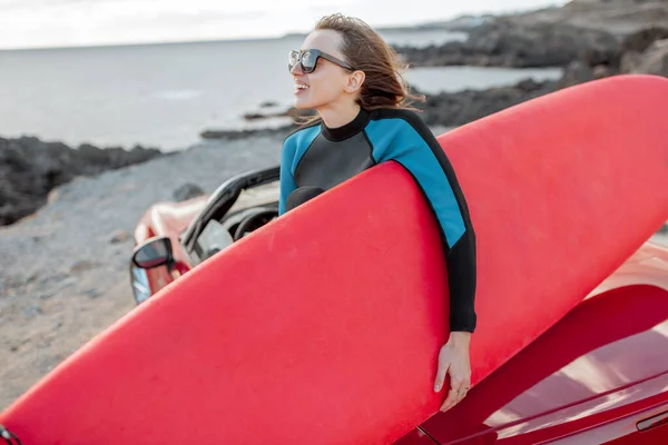 Young surfer with surfboard on the sports car on the beach — Stok fotoğraf