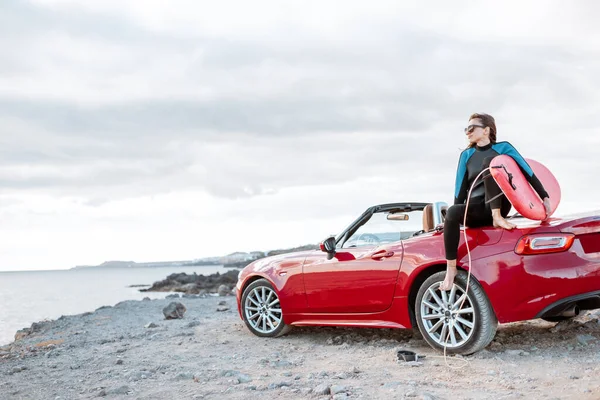 Young surfer with surfboard on the sports car on the beach — Stockfoto