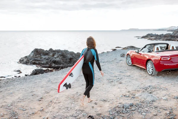 Frau mit Surfbrett an der Küste — Stockfoto