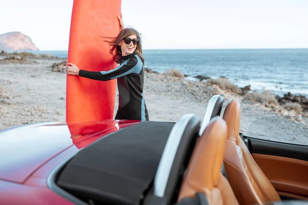 Young woman with surfboard on the rocky coast — 图库照片