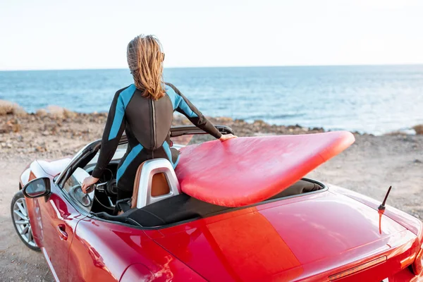 Frau mit Surfbrett im Auto in der Nähe des Ozeans — Stockfoto