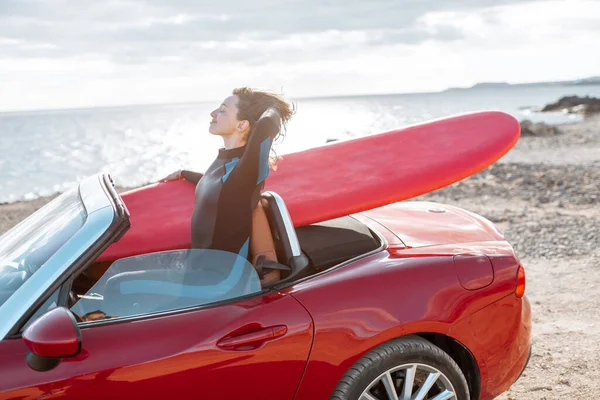 Arabasında sörf tahtası olan bir kadın okyanusun kenarında. — Stok fotoğraf