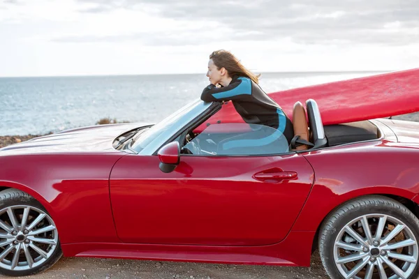 Frau mit Surfbrett im Auto in der Nähe des Ozeans — Stockfoto