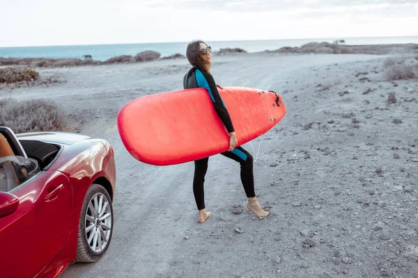 Frau mit Surfbrett an der Küste — Stockfoto