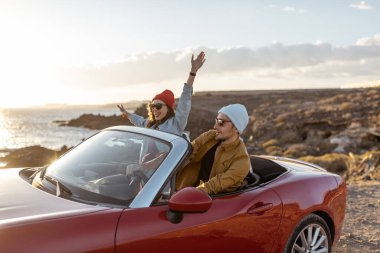 Lovely couple driving a cabriolet near the ocean