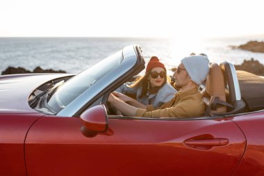 Lovely couple driving a cabriolet near the ocean