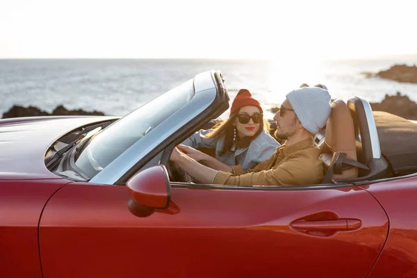 Lovely couple driving a cabriolet near the ocean — Stockfoto