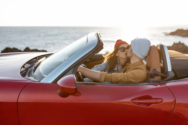 Lovely couple driving a cabriolet near the ocean — Stockfoto