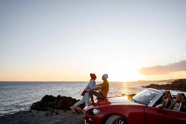 Härligt par på stranden nära bilen på en solnedgång — Stockfoto