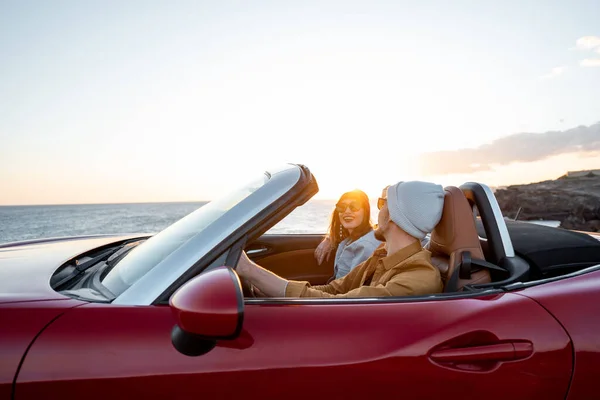Lovely couple driving a cabriolet on a sunset — 图库照片