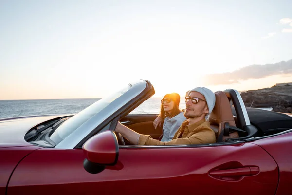 Lovely couple driving a cabriolet on a sunset — Stockfoto