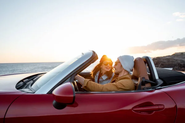 Lovely couple driving a cabriolet on a sunset — 图库照片