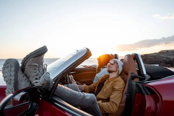 Lovely couple in the cabriolet on a sunset — Stockfoto